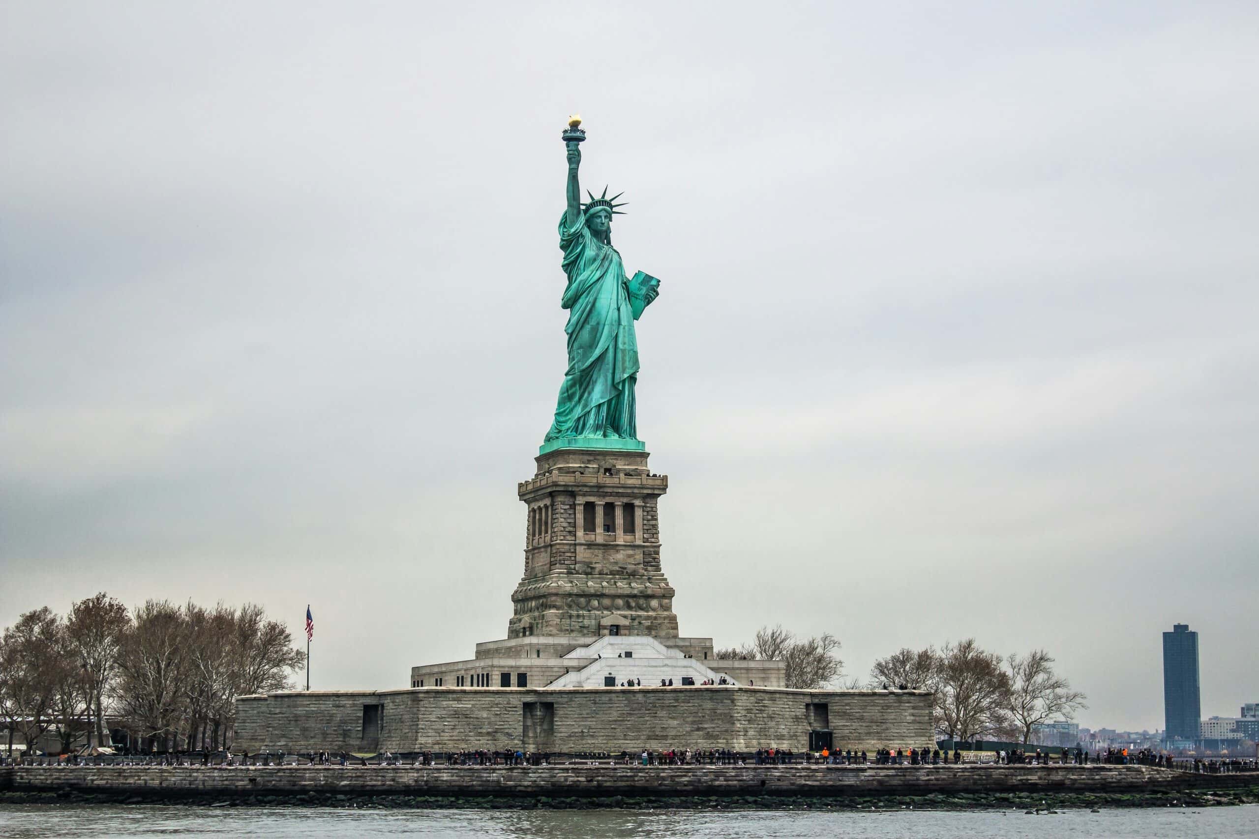 Close-up of the Statue of Liberty in New York City, capturing the iconic crown and torch against a cloudy sky.