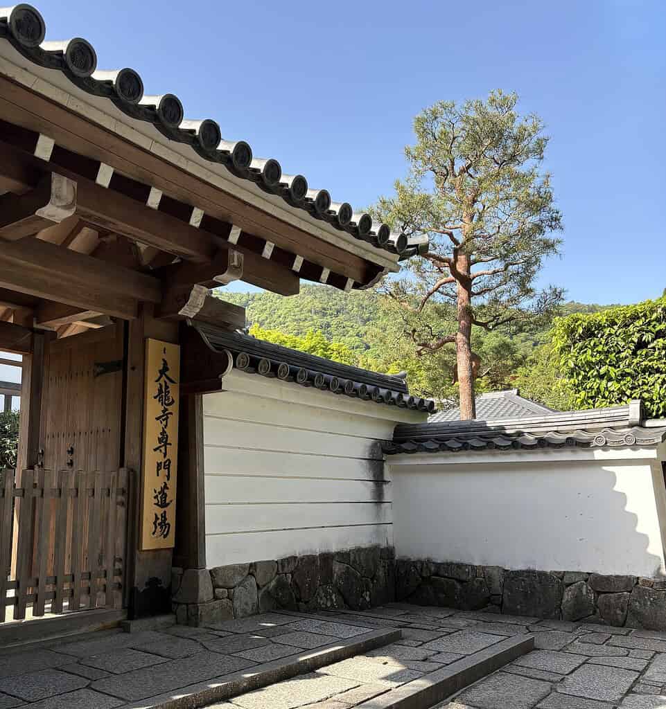 Entrance of Tenryu-Ji Temple in Arashiyama, Kyoto, with traditional Japanese architecture and scenic hill backdrop