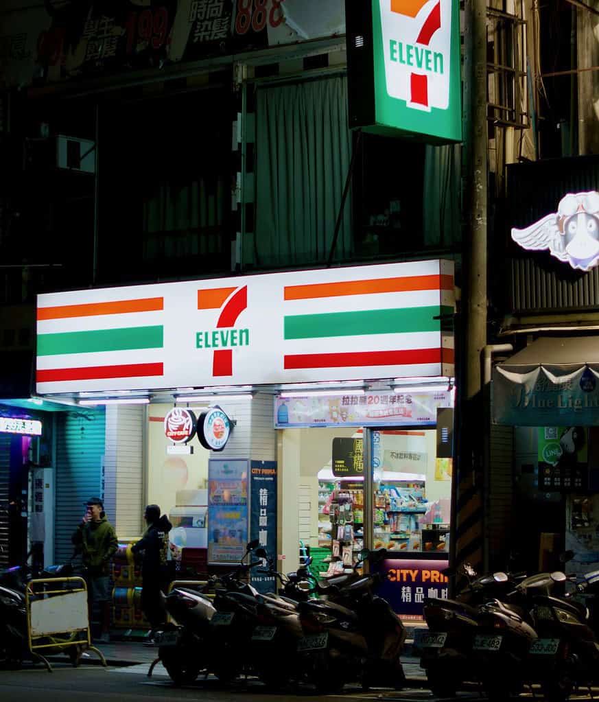 a storefront of 7 Eleven at night time, brightly lit display 