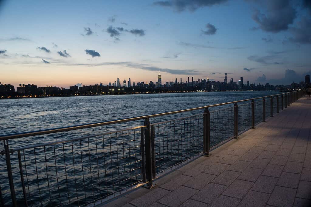 View of NYC skyline at sunset from Brooklyn boardwalk on a warm summer night