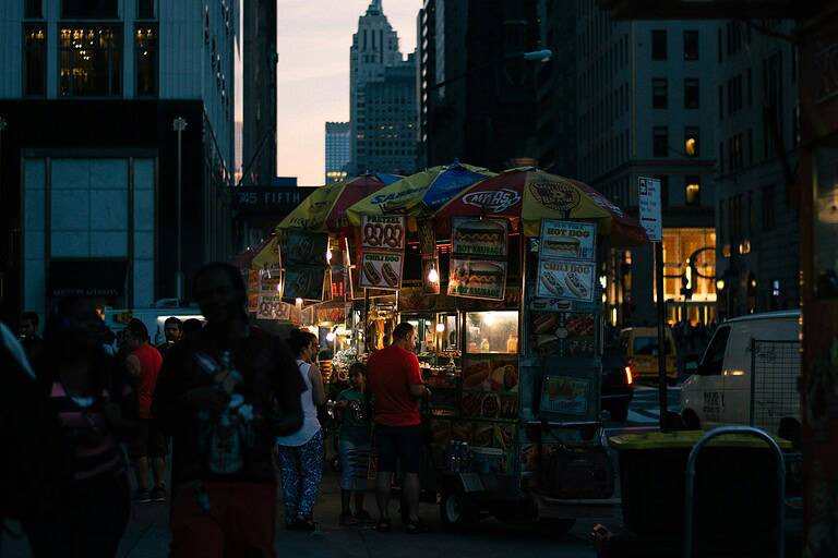 Family at hot dog stand in NYC at night with Empire State Building in background