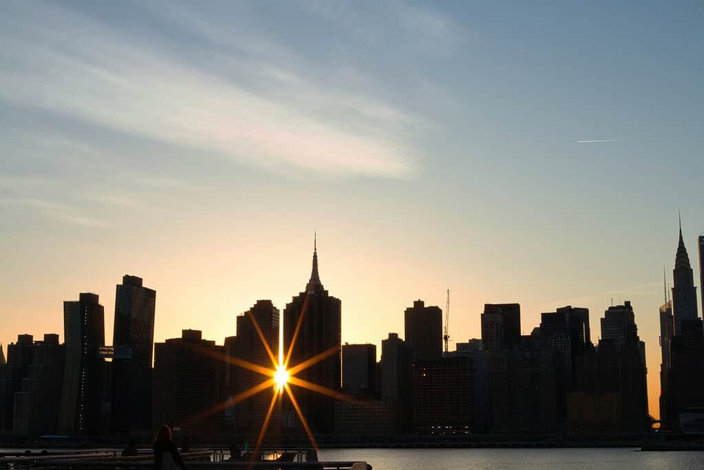 Sun shining perfectly between two buildings with the NYC skyline in view