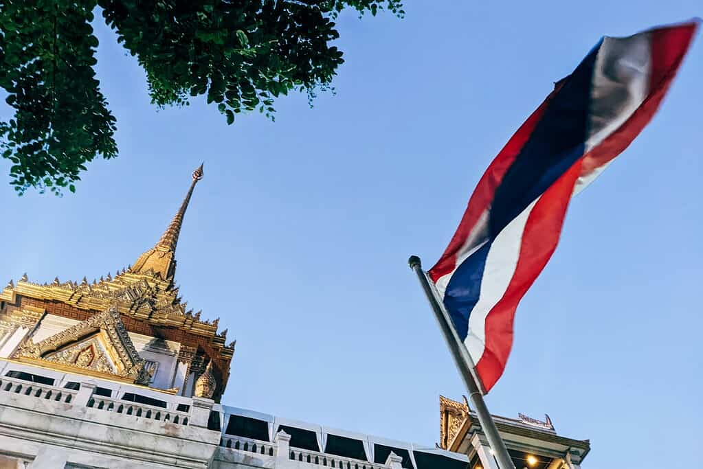 Thai temple with national flag waving under clear blue skies