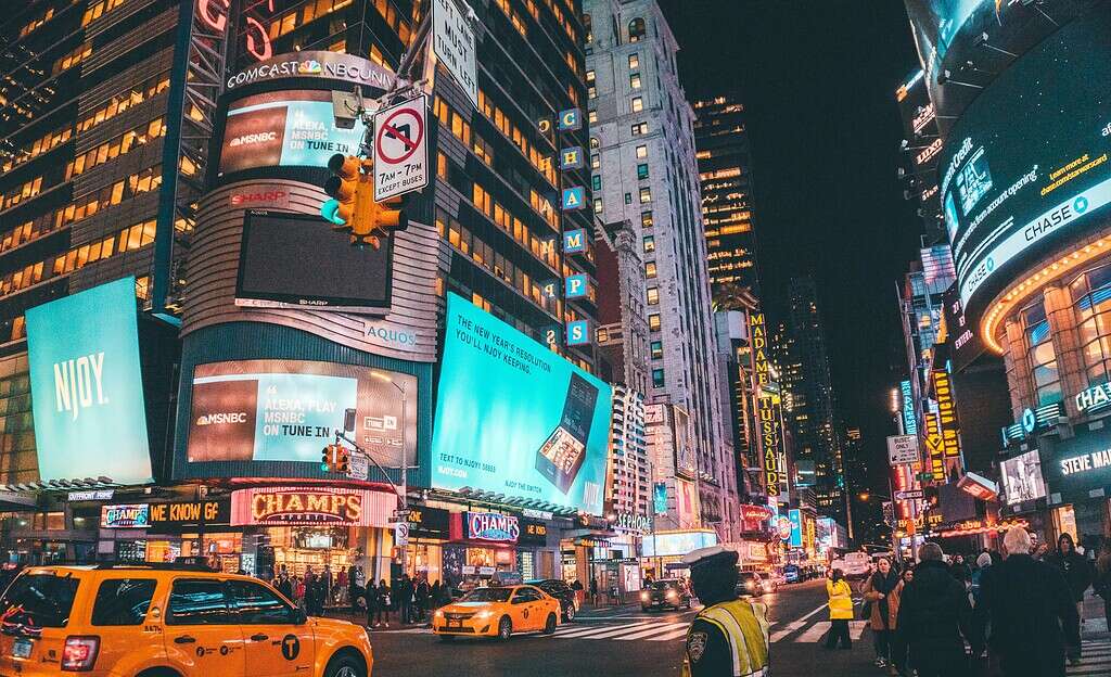 Times Square in NYC with yellow cabs, tourists walking, and locals on a busy street