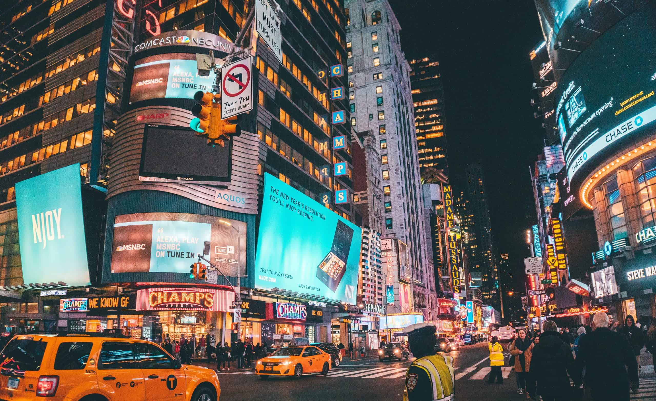 Times Square in NYC with yellow cabs, tourists walking, and locals on a busy street