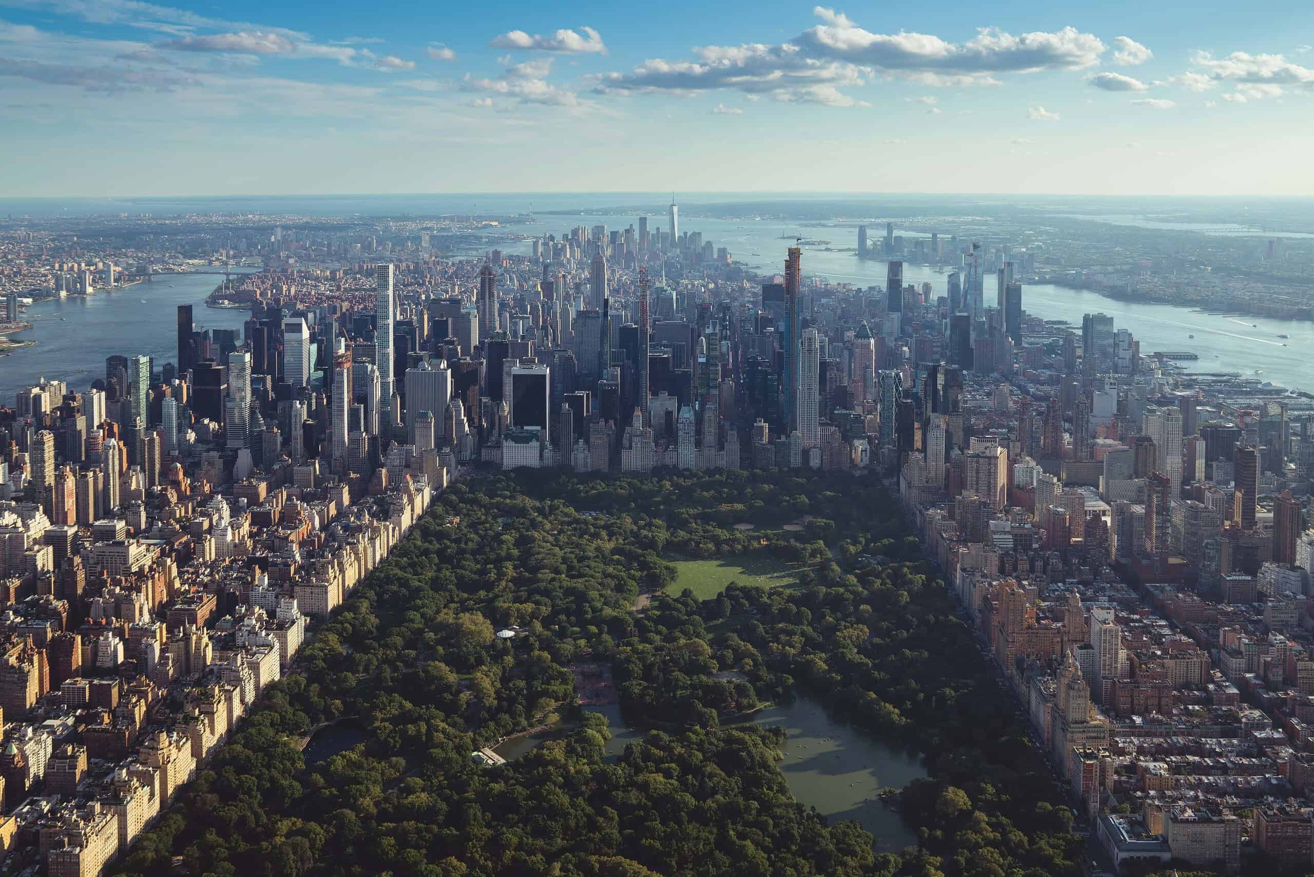 Helicopter view of Central Park in NYC surrounded by city buildings and urban greenery
