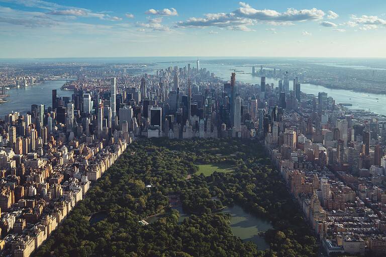 Helicopter view of Central Park in NYC surrounded by city buildings and urban greenery