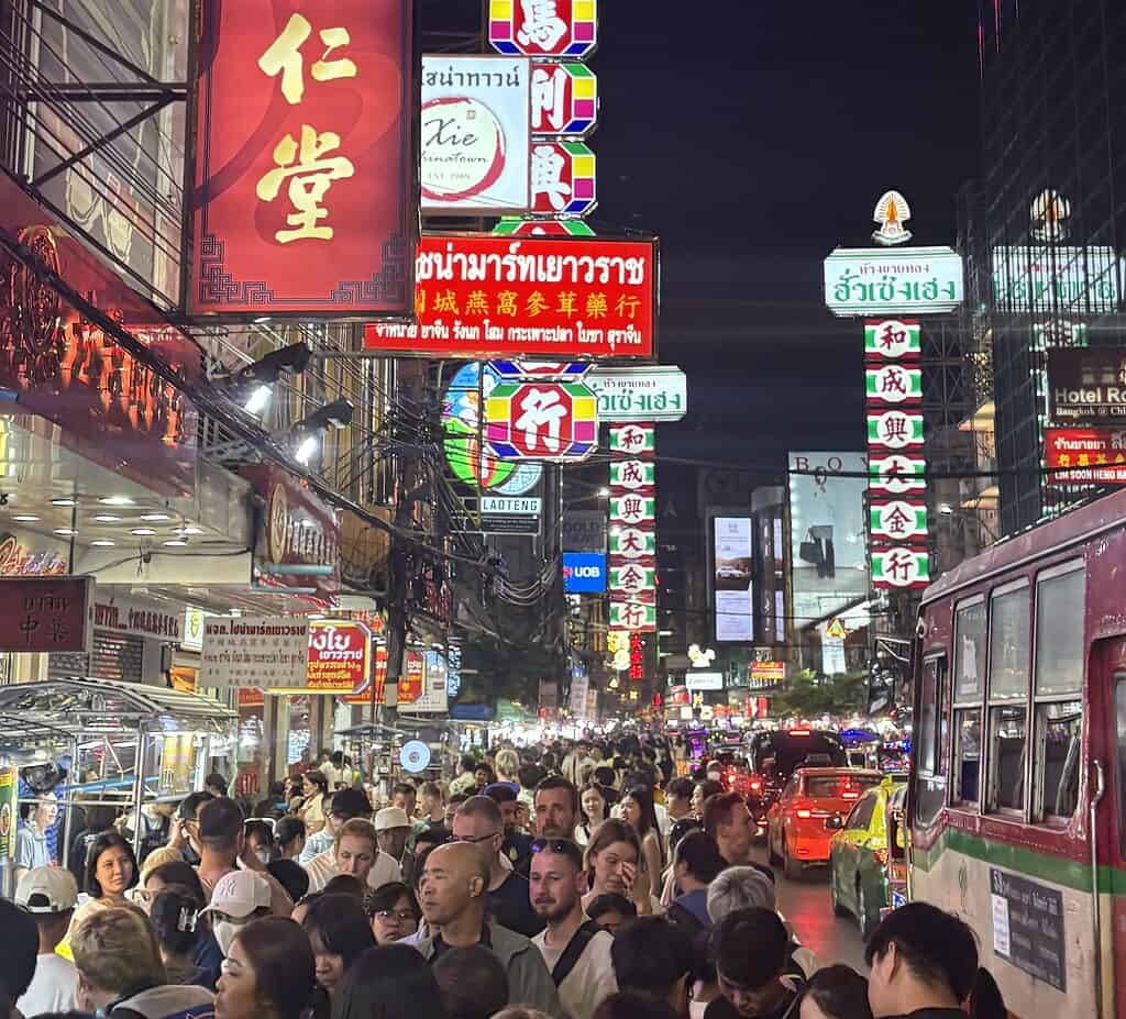 Bustling Yaowarat Road in Bangkok’s Chinatown at night, filled with tourists, bright lights, and heavy traffic