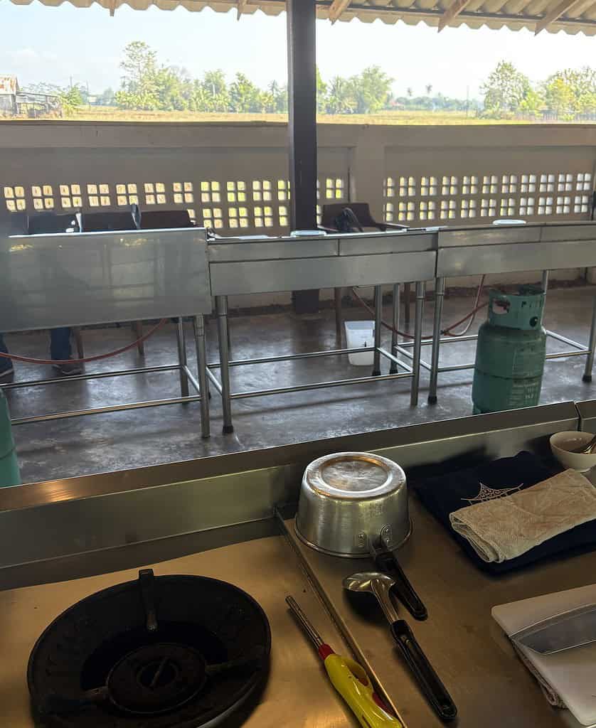 Outdoor cooking station with a farm in the background at a Thai cooking class in Chiang Mai, Thailand