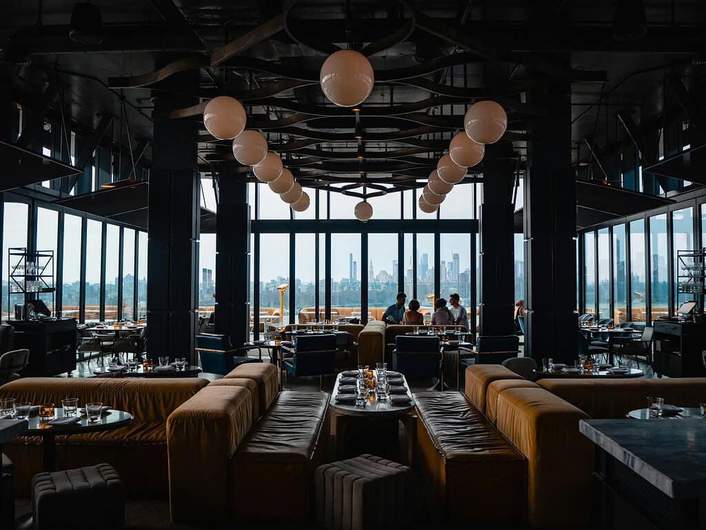 Interior of Westlight Bar in Brooklyn, New York, featuring sleek modern design with floor-to-ceiling windows overlooking a panoramic view of the city skyline.