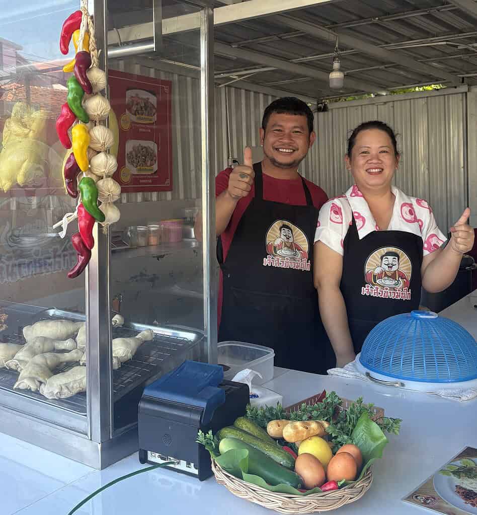 Couple smiling outside their chicken restaurant in Chiang Mai, Thailand.