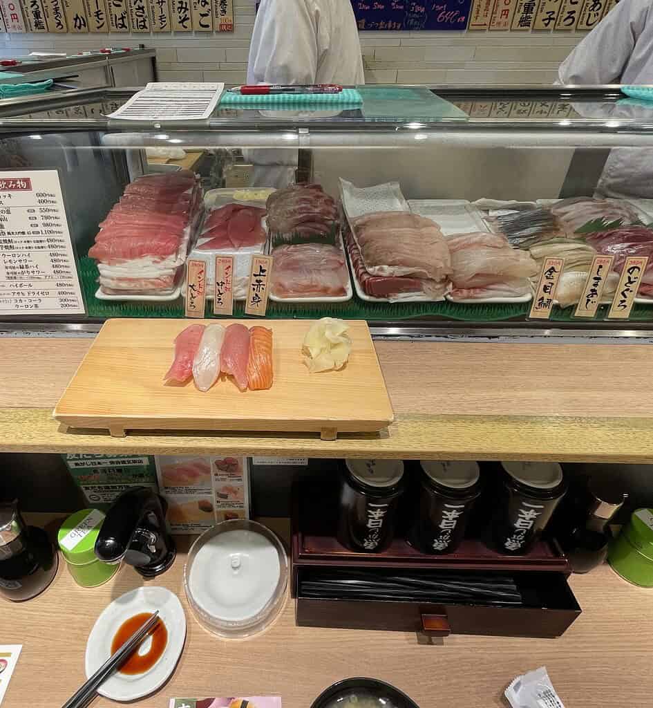 plenty of fresh fish behind class in Tokyo at a stand up sushi bar 