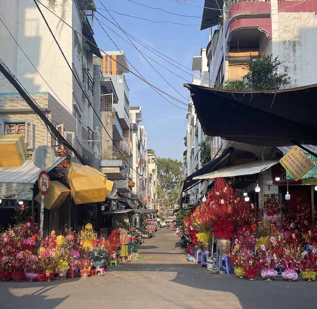 Colorful Tet flower market lining a street in Ho Chi Minh City Vietnam with red and yellow blossoms for sale before the holiday