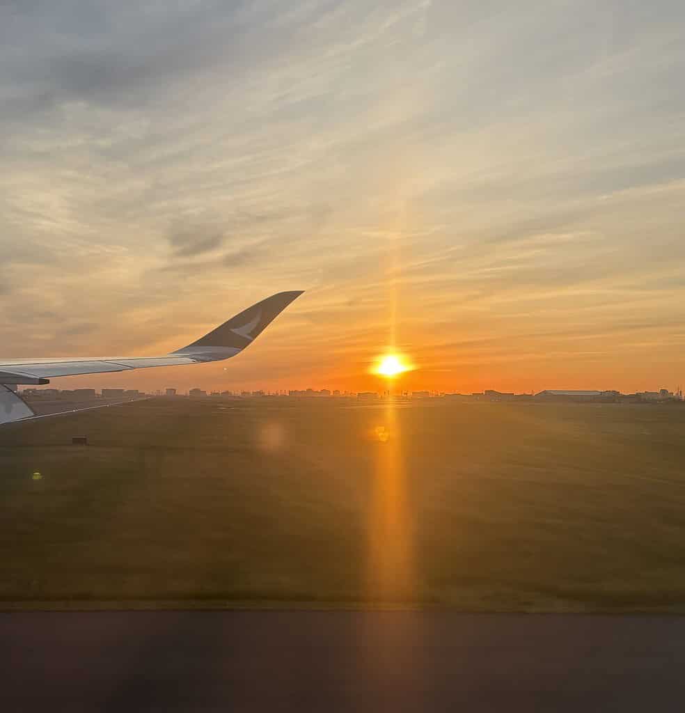 sunrise and airplane wing landing at an airport