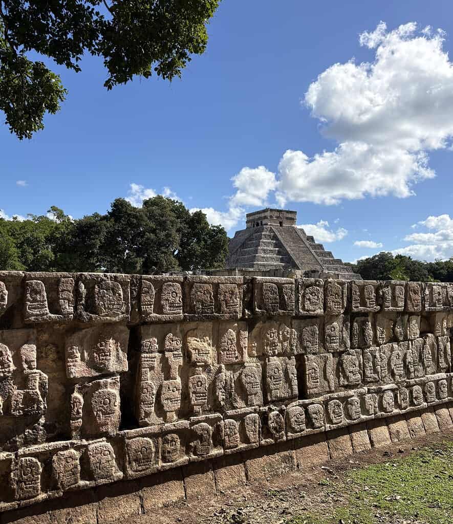 ancient Mayan wall and chichen itza pyramid in the distance in Mexico