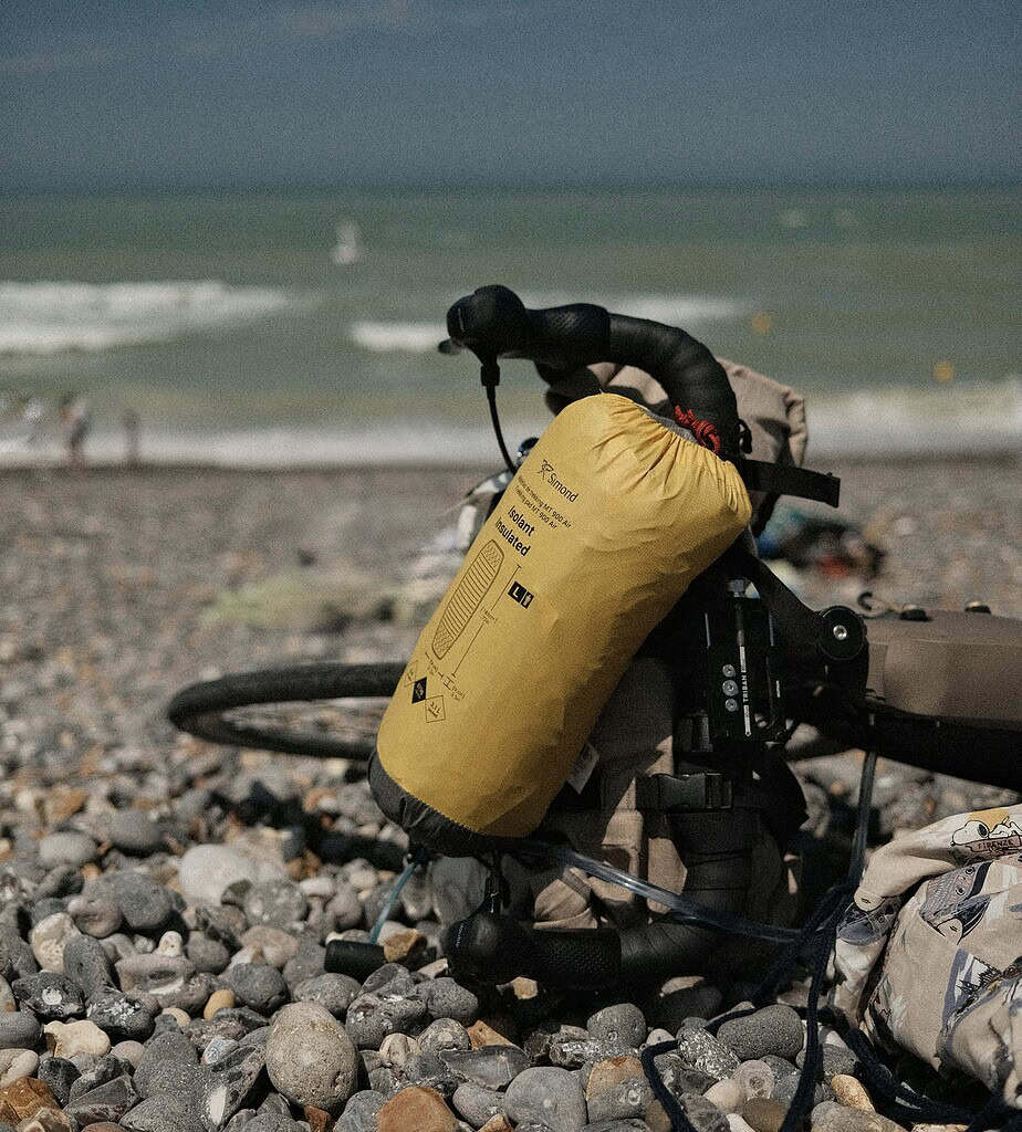 a yellow dry bag full of items on the beach 