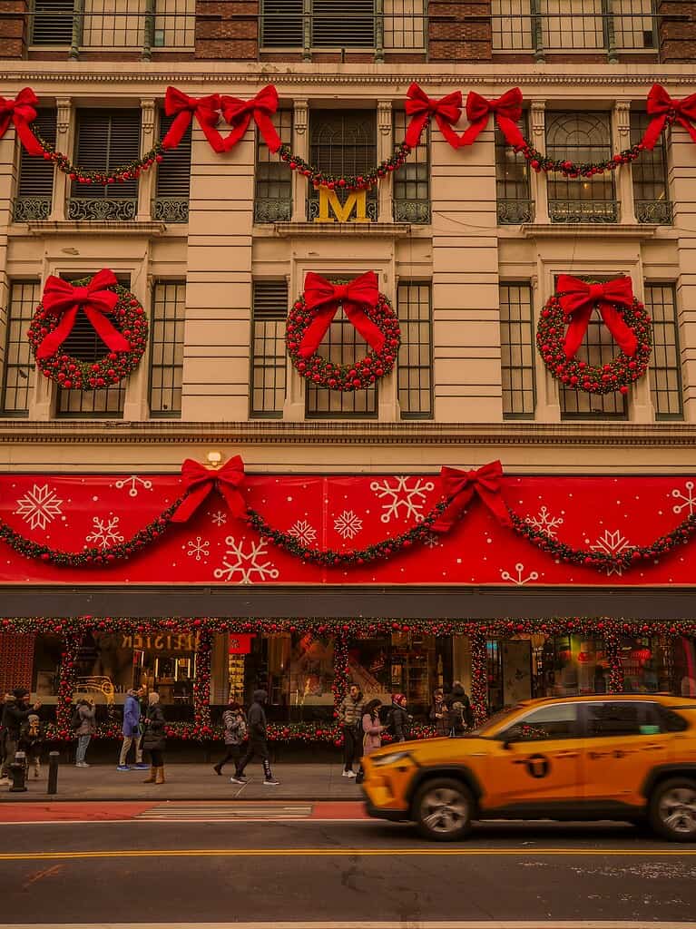 Plenty of red and green Christmas decor outside of a building in NYC during the holiday time