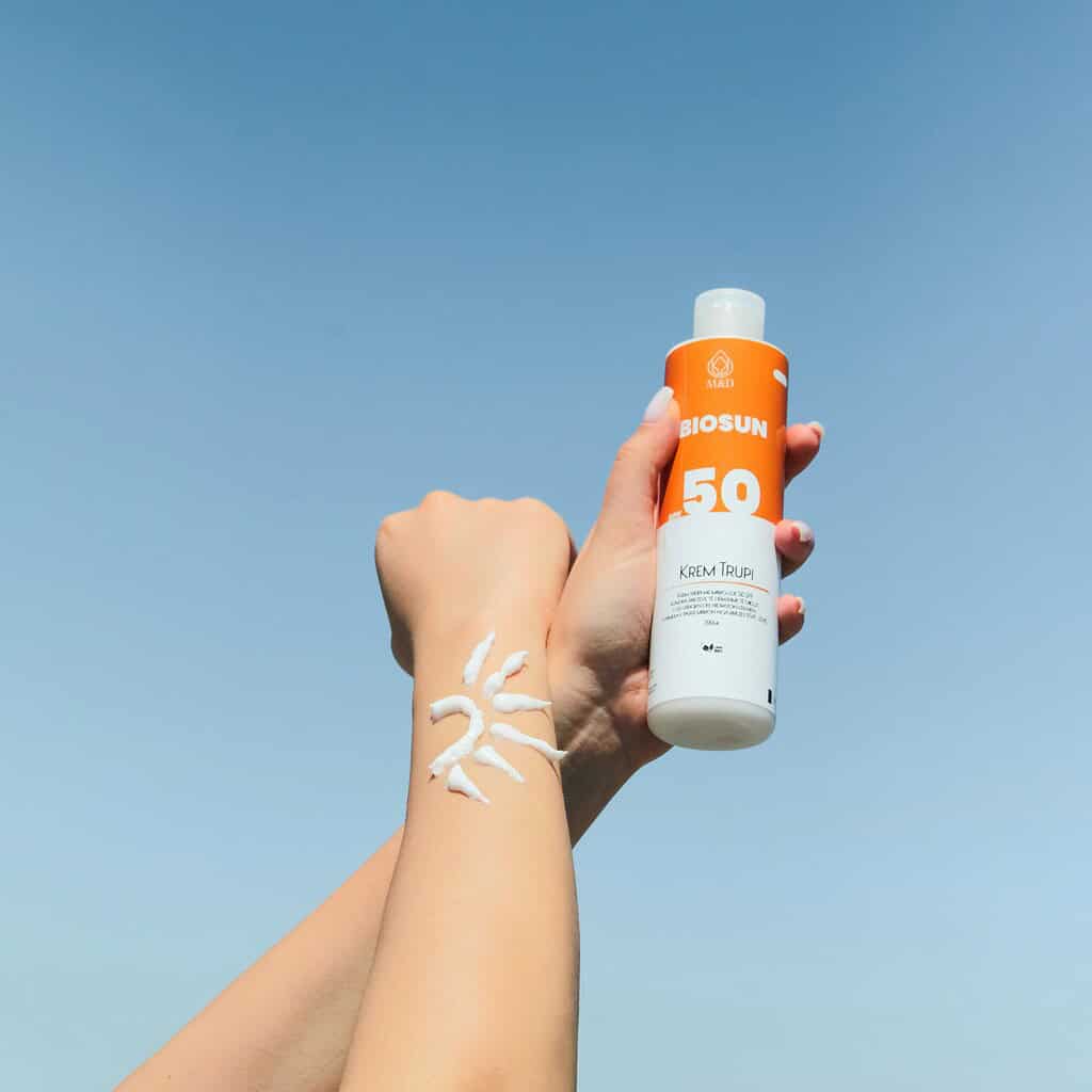 sunscreen held and used with blue skies in the background 