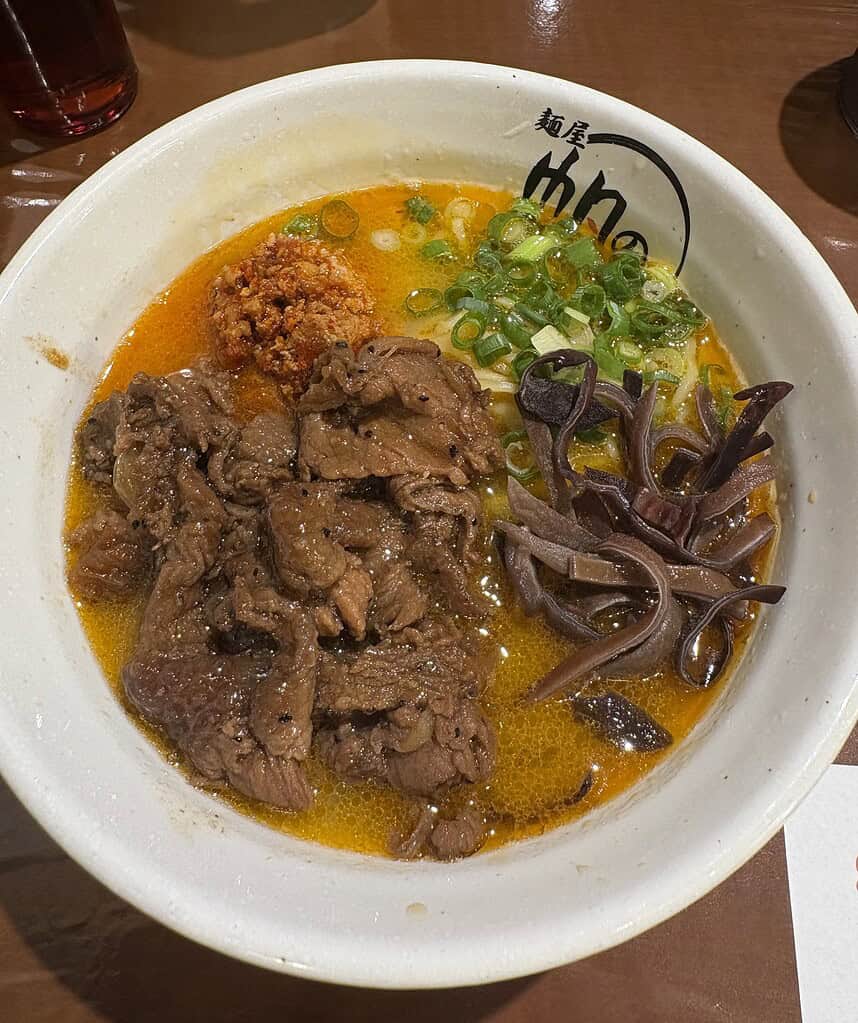 a bowl of spicy ramen topped with beef  